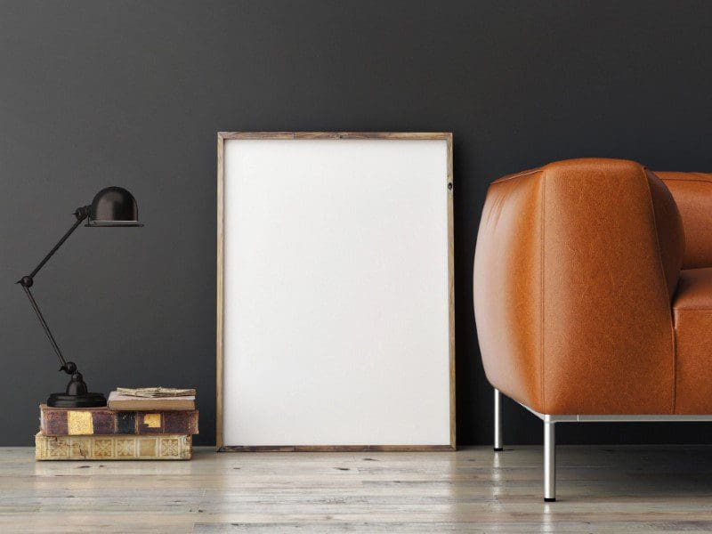 A chair and picture frame in front of a wall.