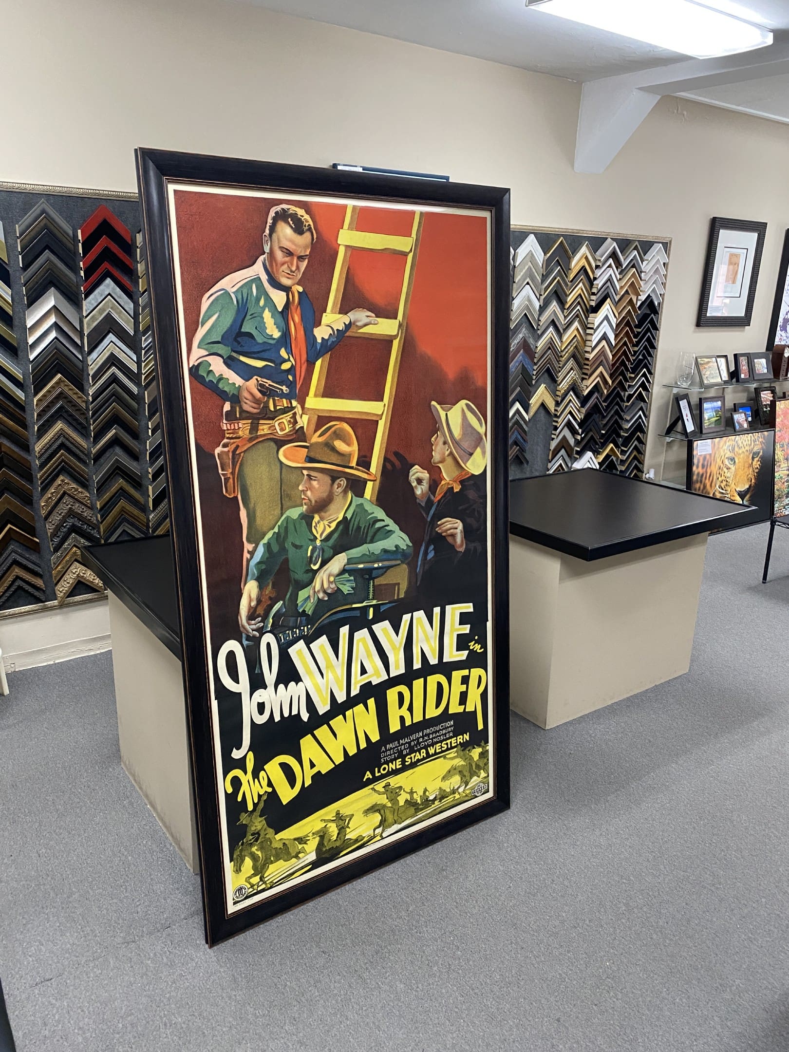 A large framed movie poster of john wayne in the dark rider.