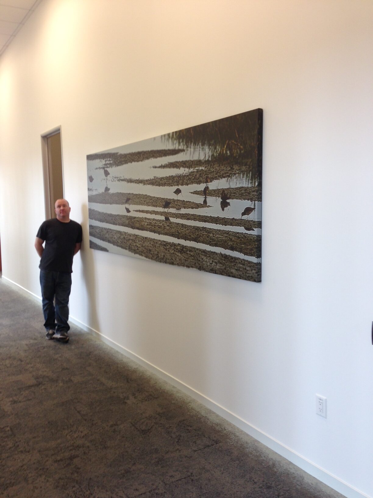 A man standing in front of a painting on the wall.